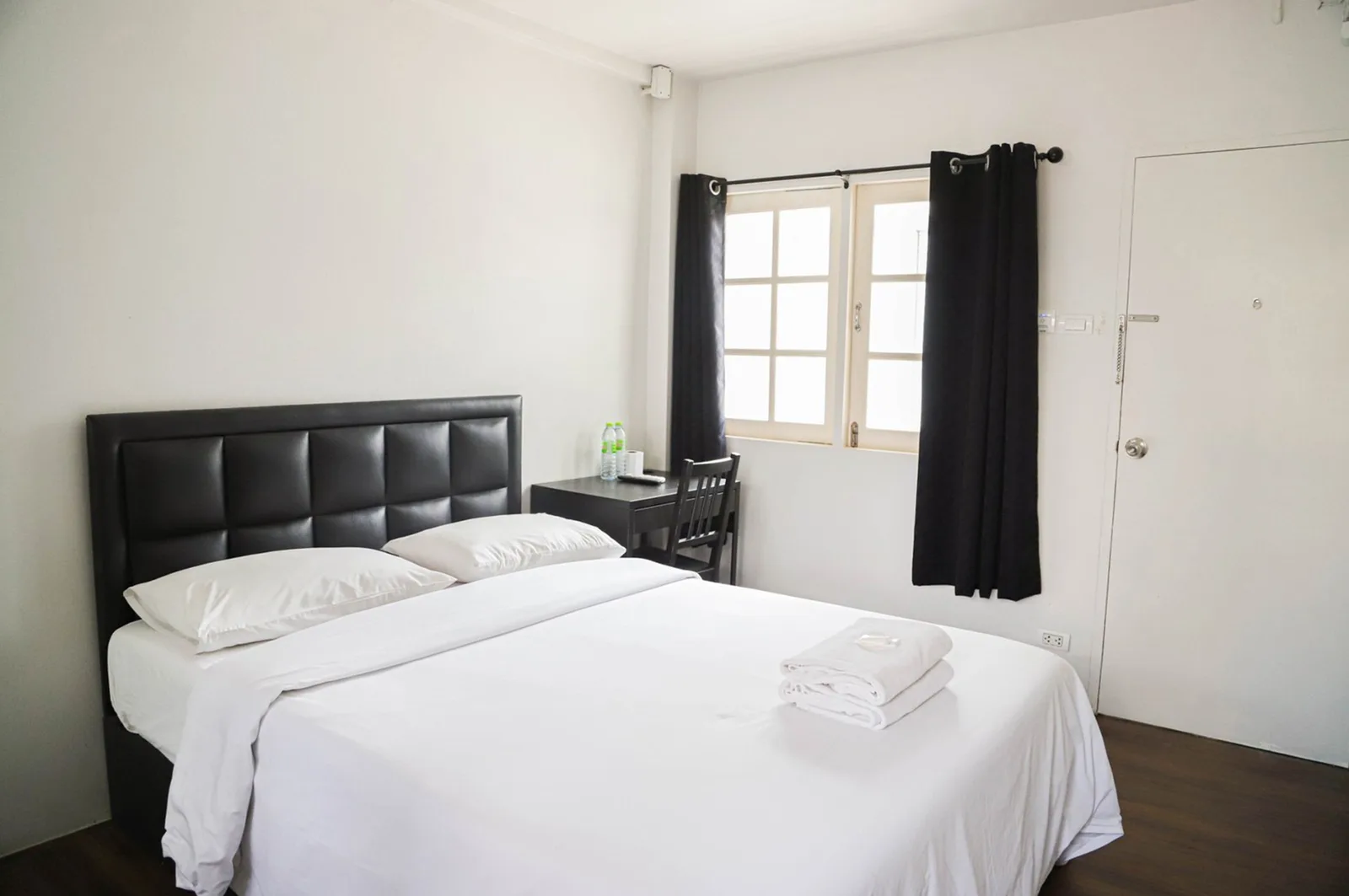 Standard Double room with a black leather headboard and crisp white bedding